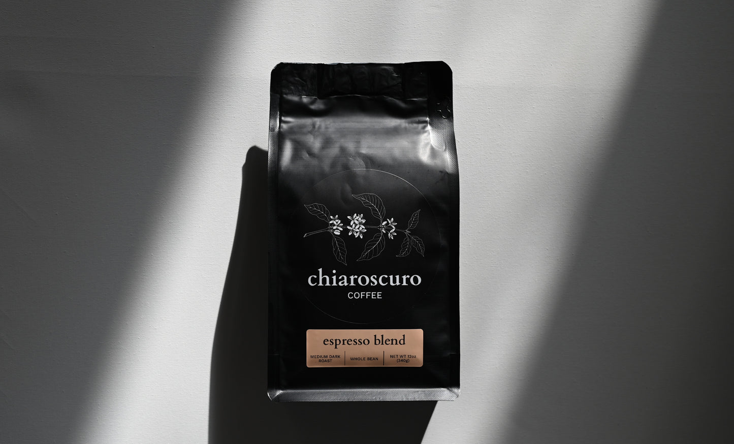 Chiaroscuro Coffee espresso blend, medium dark roast, whole bean, 12 oz package, elegant black design.