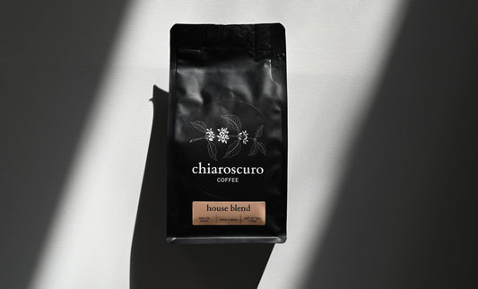 Chiaroscuro coffee house blend, medium roast, whole bean, 12 oz black packaging on a light background.